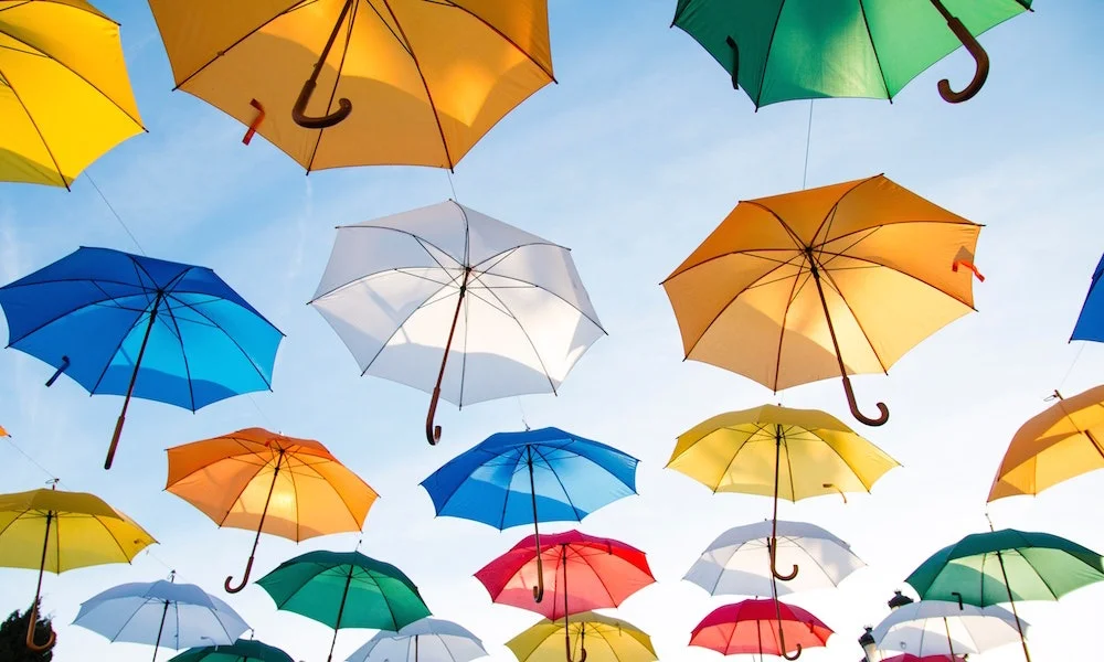 Image illustrant l'assurance prévoyance en montrant des parapluies qui lévitent dans le ciel.