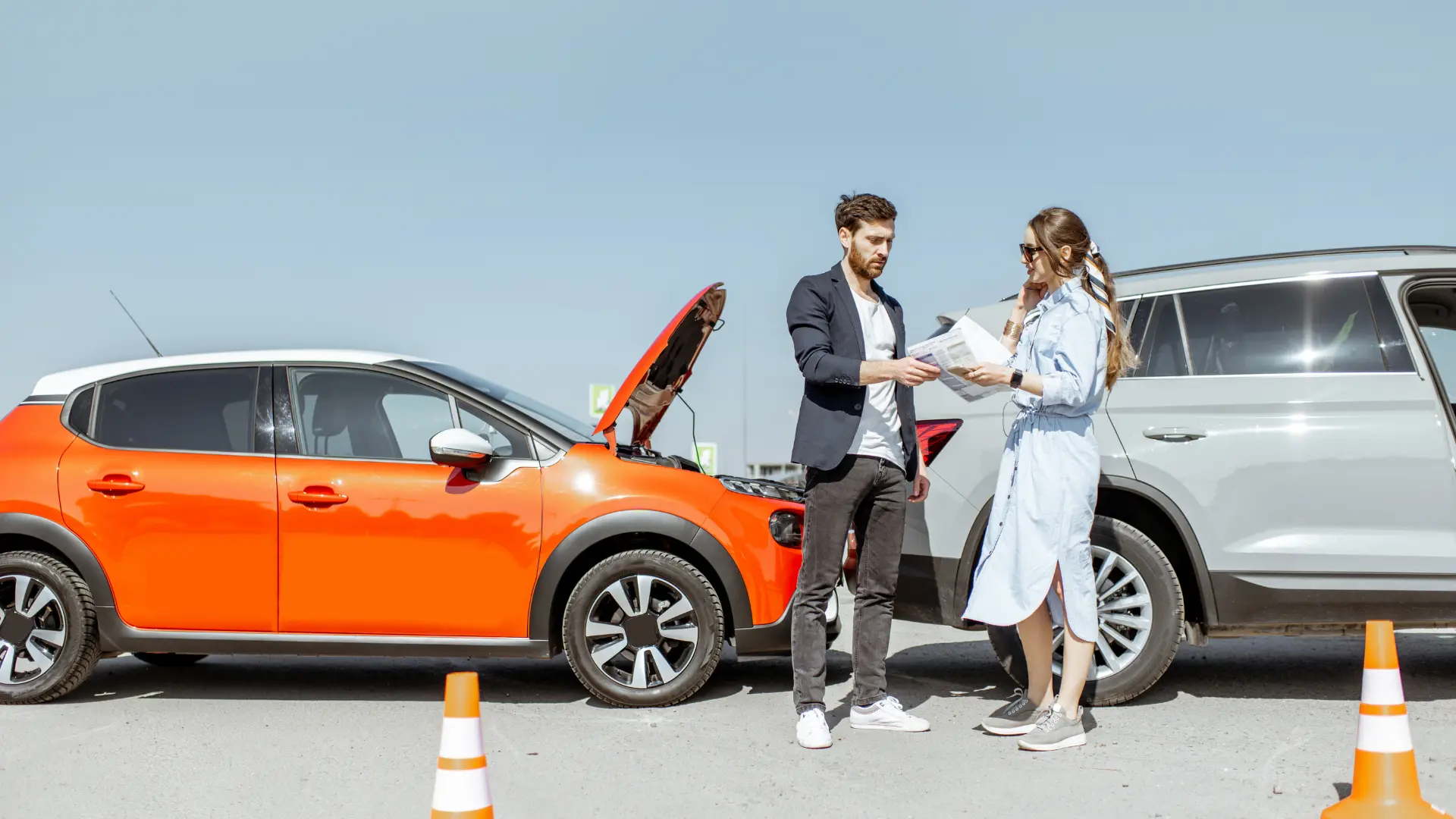 Un homme et une femme arrêtés sur le bas côté de la route pour faire un constat amiable suite à un accident de voiture.