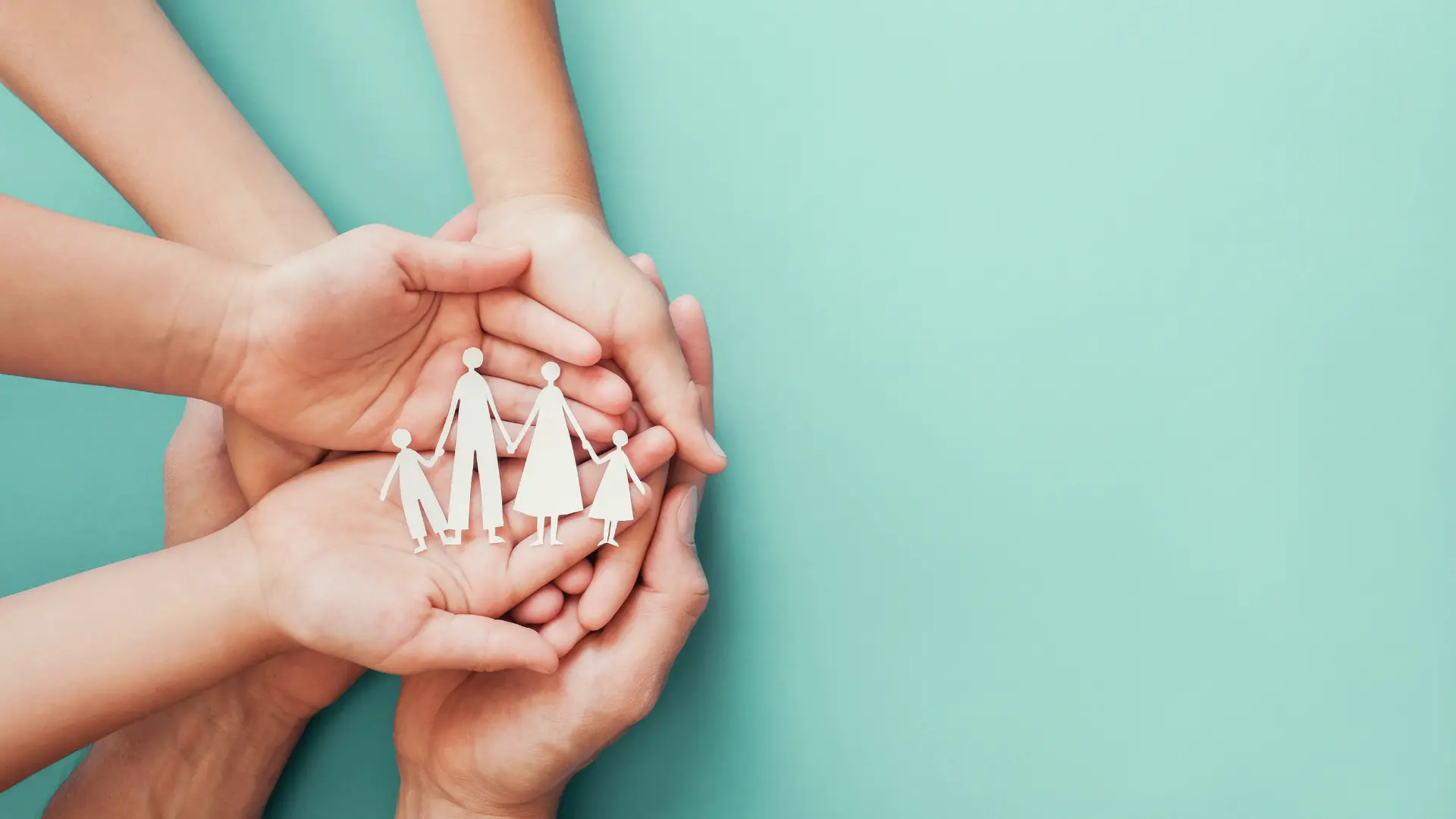 Plusieurs mains tiennent un papier découpé représentant une famille sur un fond bleu.