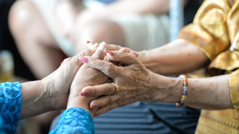Deux personnes âgées se tenant les mains, image illustrant un article de Prestacourtage parlant de l'assurance dépendance.